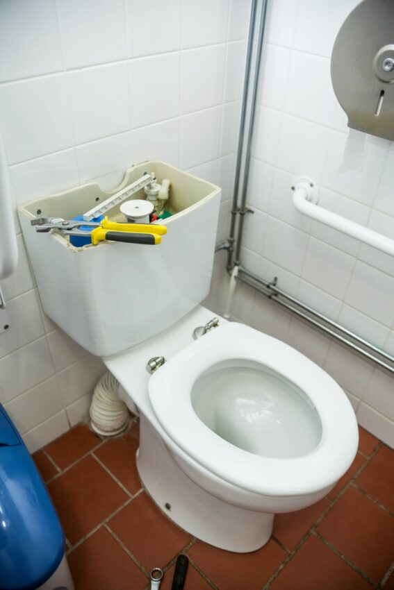 toilet open and being repaired with tools